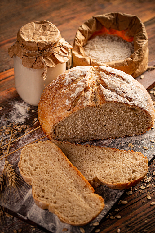 Cut loaf of artisanal wheat bread in a wooden background