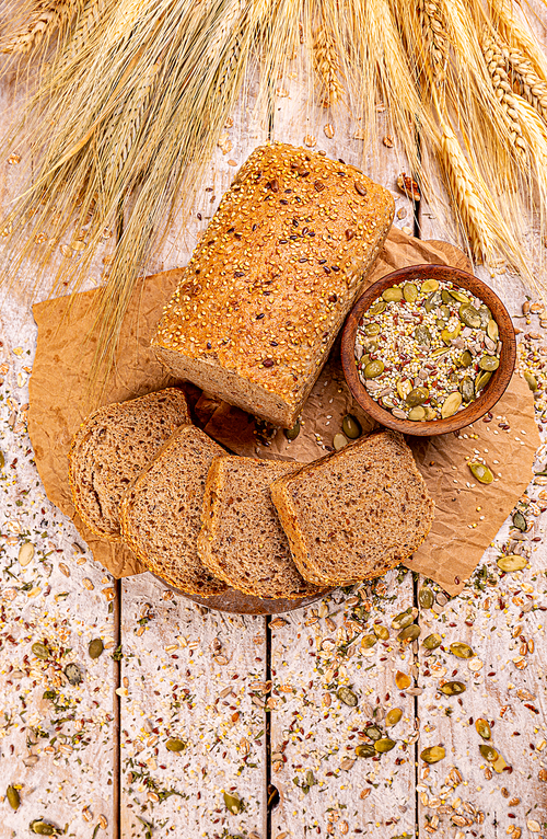 Flat lay of loaf of bread with seeds on wooden background