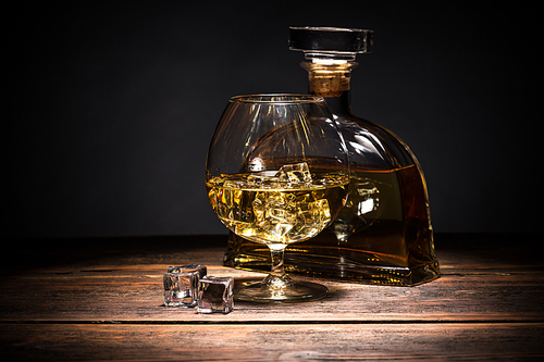 Half full glass of cognac on a wooden surface