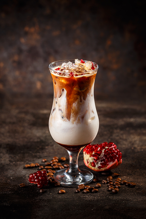 Glass of tasty pomegranate flavored coffee latte on vintage dark background