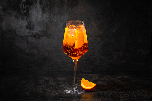 Glass of aperol spritz cocktail on black background