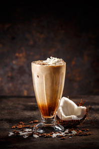 Glass of cold tasty coconut coffee on vintage dark background