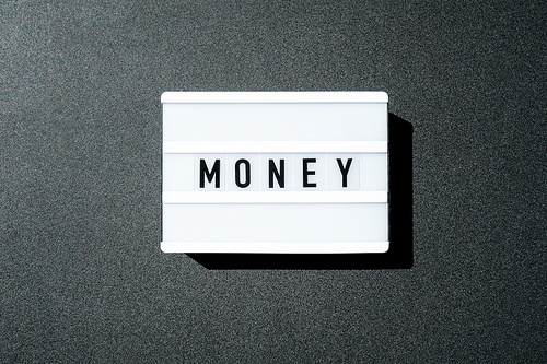 Lightbox board on a black background with the words MONEY in black letters. Currency, cash