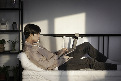 집에서 노트북을 사용하는 잘생긴 청년. 그의 방에서 쉬고 있는 학생 남자. 숙제 또는 공부, 프리랜서, 온라인 학습 및 커뮤니케이션 컨셉