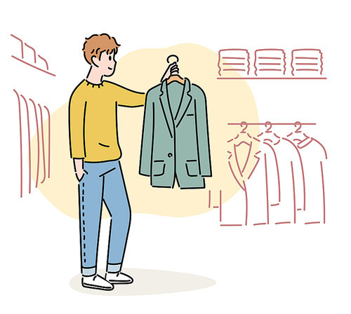 한 남자가 옷가게에서 자켓을 들어올려 보고 있다.