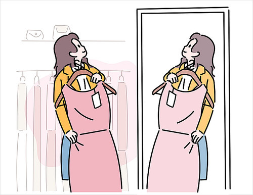 한 여성이 옷가게에서 드레스를 몸에 대보고 있다.
