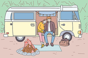 남자와 여자가 캠핑카에 앉아 모닥불을 보고 있다.