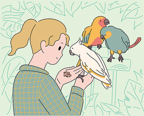 한 소녀가 손에 앵무새를 올려놓고 먹이를 주고 있다.