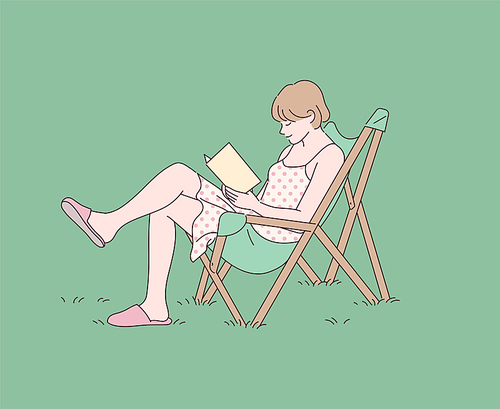 잔디밭에서 의자를 펴고 책을 읽고 있는 소녀