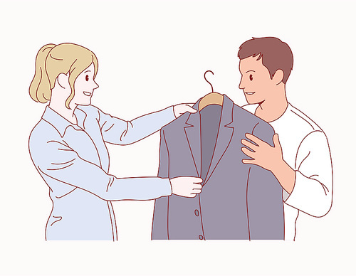 한 여성이 남자에게 자켓을 골라 주고 있다.