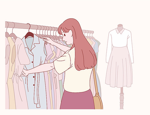 한 소녀가 옷가게에서 옷을 고르고 있다.
