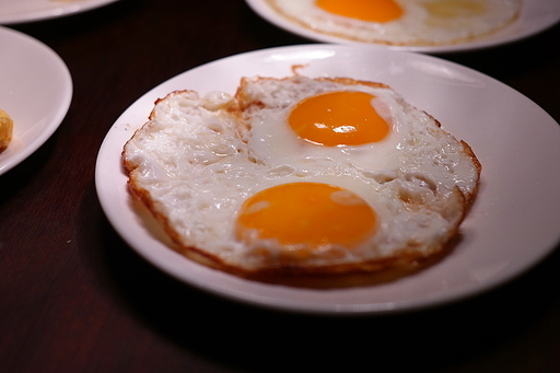 흰 접시에 촉촉한 계란후라이 반숙이 제공됩니다