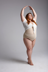 Plus size Caucasian woman imitating ballet dancer while wearing swimsuit