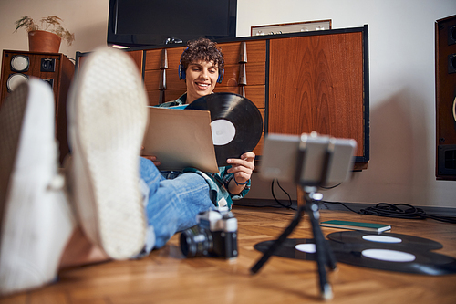 Handsome smiling guy sitting on the floor and holding vinyl record stock photo