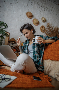 Pretty lady looking on laptop while holding coffee stock photo