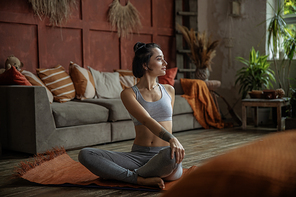 Full length portrait of a young woman sitting on a yoga mat