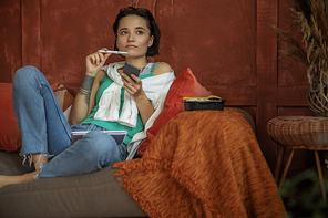 Woman sitting on sofa with mobile phone stock photo