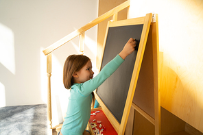 Adorable child drawing on blackboard with chalk stock photo