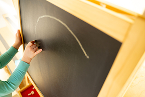 Close up of child hand drawing on blackboard with chalk in children playroom stock photo