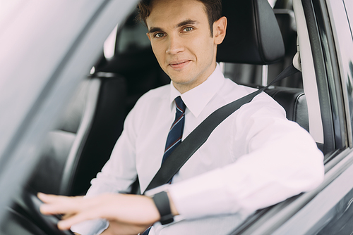 Cheerful man in tie and classic shirt is sitting in car