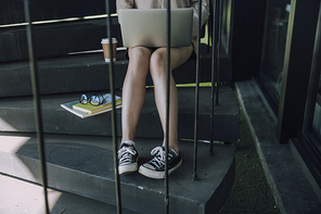Young sitting on stairs with laptop indoors. Education concept