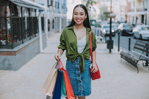 Smiling Asian lady with bags in the city stock photo