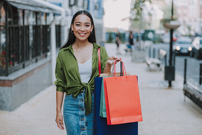 Smiling Asian lady showing shopping bags stock photo