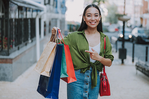Smiling Asian woman walking with shopping bags stock photo