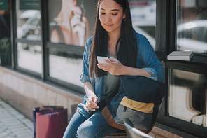 Young woman with smartphone sitting in the city stock photo