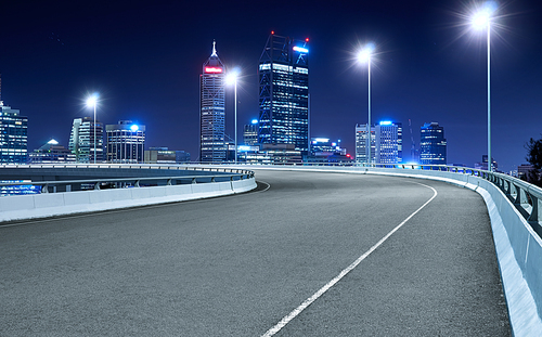 High speed corner overpass asphalt road with Perth cityscape , night scene .