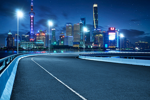 High speed corner overpass asphalt road with Shanghai cityscape , night scene .