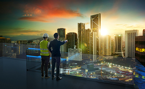 Businessman and developer engineer standing on open roof top balcony discuss about development of the future with beautiful cityscape sunrise view . Business ambition and vision concept .