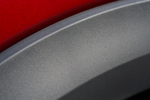 Close up detail of red metallic paint coating and carbon mat grey wrap car body