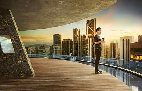 Young businessman enjoy the coffee in the early morning at open space balcony with beautiful city skyline background .