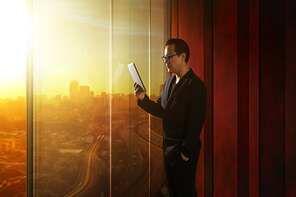 Young asian businessman holding and using digital tablet . Sunrise scene .