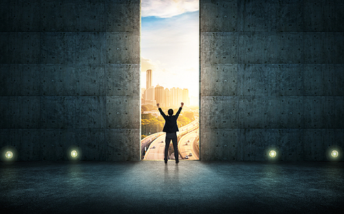 Success  businessman cheering against concrete wall with huge door ,sunrise scene city skyline outdoor view .