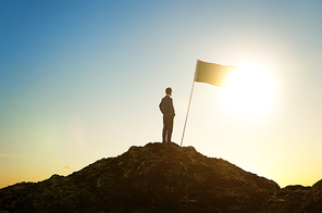 Success and achievement concept , silhouette of businessman with flag on mountain top .