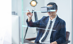Asian businessman wearing virtual reality goggle and pointing business growth chart in a office .