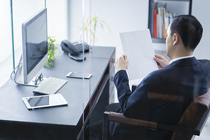 Young business man holding blank paper in hands while looking at the office