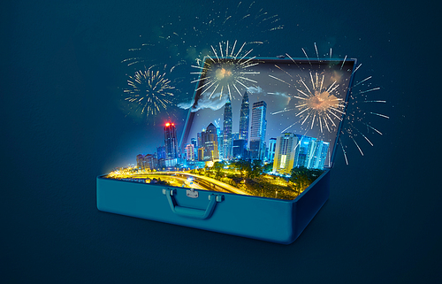 Night scene modern city skyscraper with fireworks in an open retro vintage suitcase isolated on blue background .