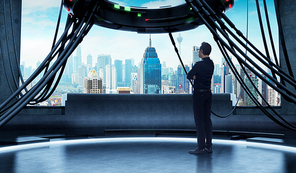Young businessman looks out city outside from high-tech control room . Mixed media .
