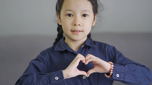 Beautiful little asian girl making a heart shape hand gesture, love and friendship forever concept