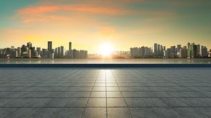 Empty concrete tiles floor with city skyline background. Sunset scene