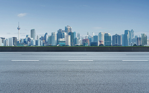 Empty asphalt road with city background, daytime scene.