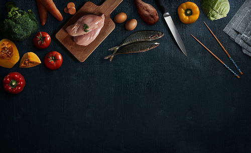 Various healthy raw food and ingredients ready for cooking on black wooden background . Delicious and tasty food cooking concept . Top view .