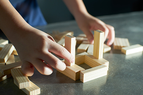 Hand of kid playing a blocks wood tower game of architectural project .Selected focusing .