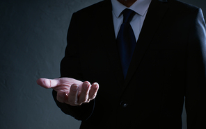 Businessman  in black suit lending a helping hand, isolated on white