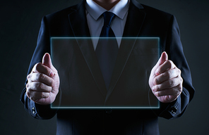 Businessman holding a clear glass empty virtual screen template, notice purpose and information using ideal concept .
