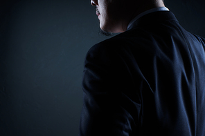 Closeup three quarter rear view of businessman with black background