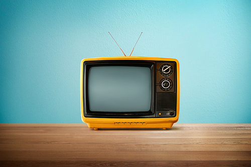 Yellow Orange color old vintage retro Television on wood table with mint blue background .